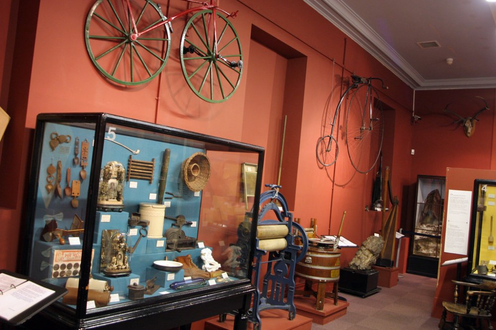 Artefacts in a glass cabinet and on the wall at Swansea Museum 