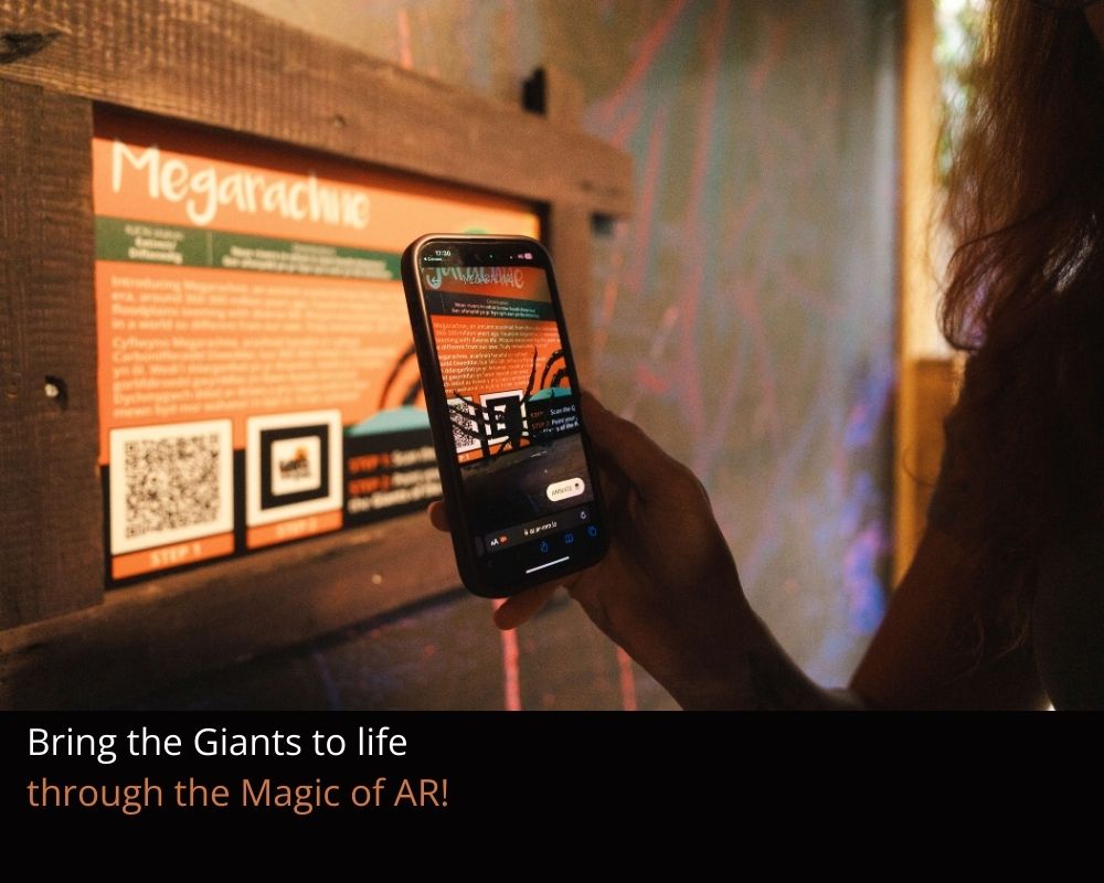 A person holding a mobile phone pointed at a sign with information about Megarachne